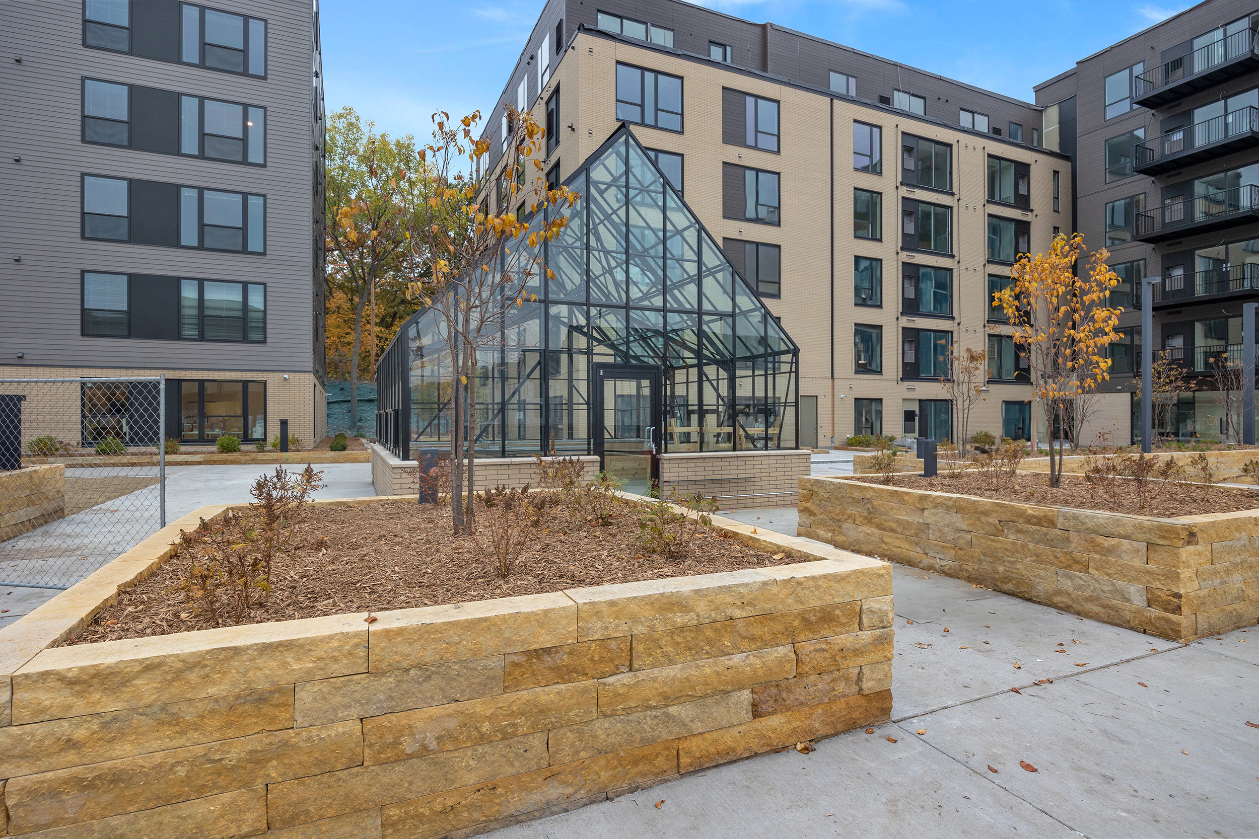 An exterior photo of two new apartments conjoined by a large greenhouse in a courtyard